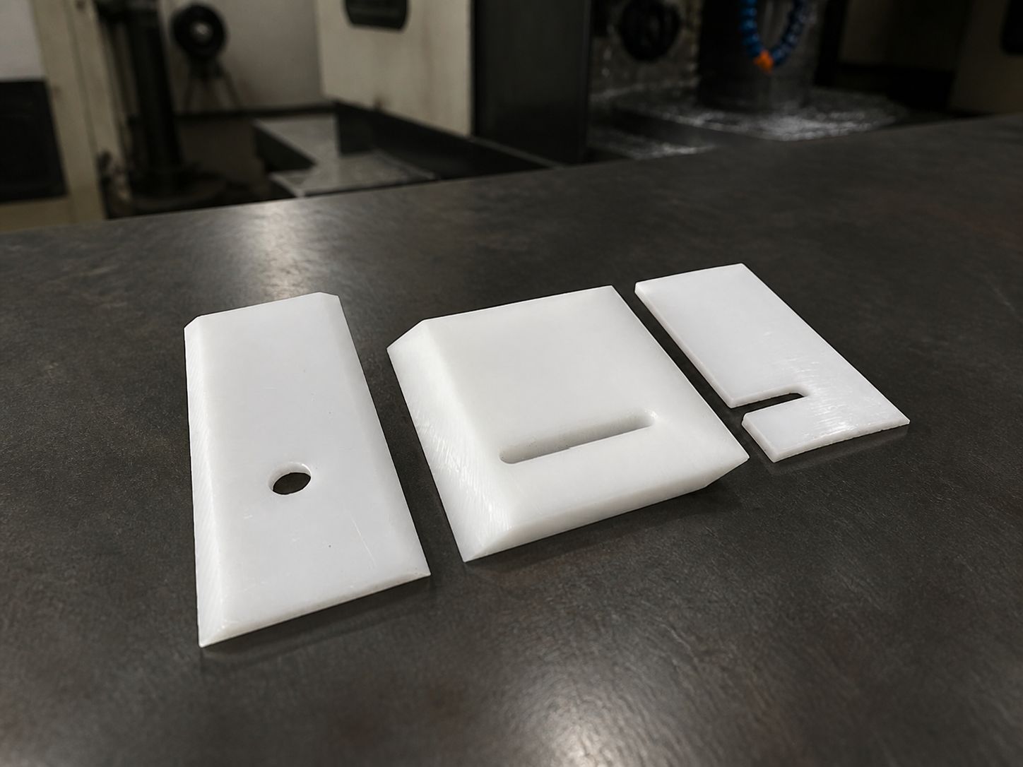 Three small white blades side by side showing a round hole, a vertical slot and a corner notch.