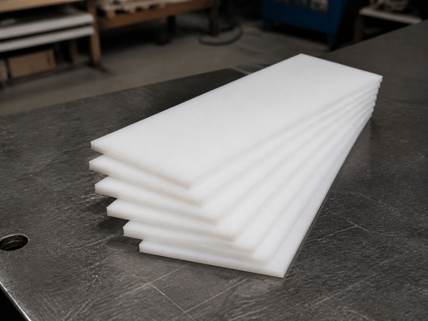 Six thin white blade blanks fanned in a stack on a steel bench.