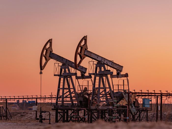 Two pump jacks working an oil field at sunset.