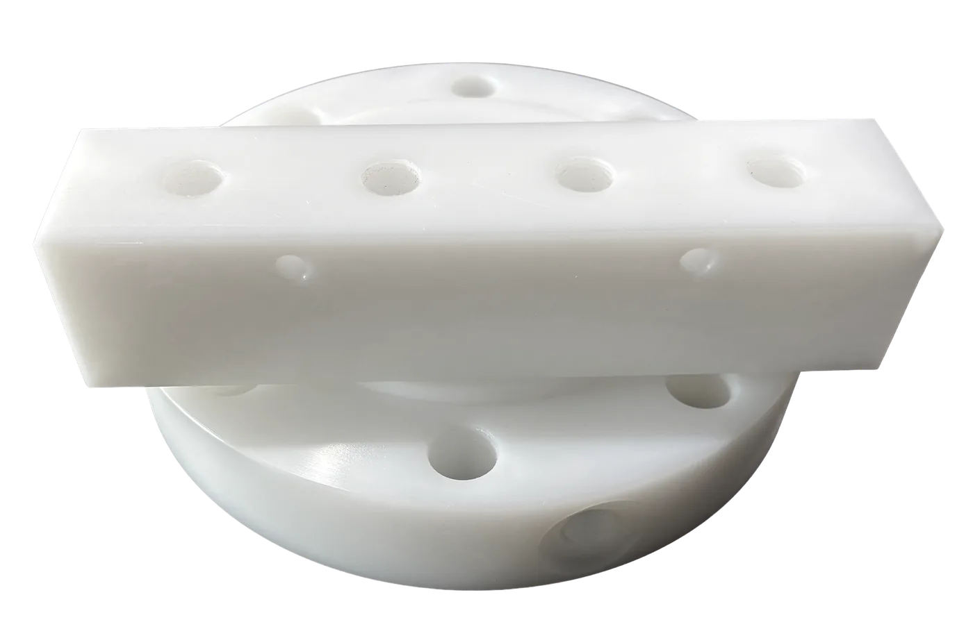 A drilled UHMW wear bar resting on a flanged wear ring, both machined from solid stock.